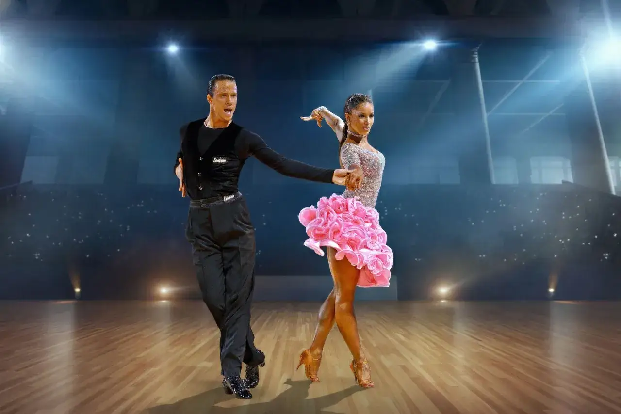 Coppia di ballerini in abito da sera, lei con un vestito rosa svolazzante, lui in nero. Un'esibizione di salsa danza che incanta il pubblico.