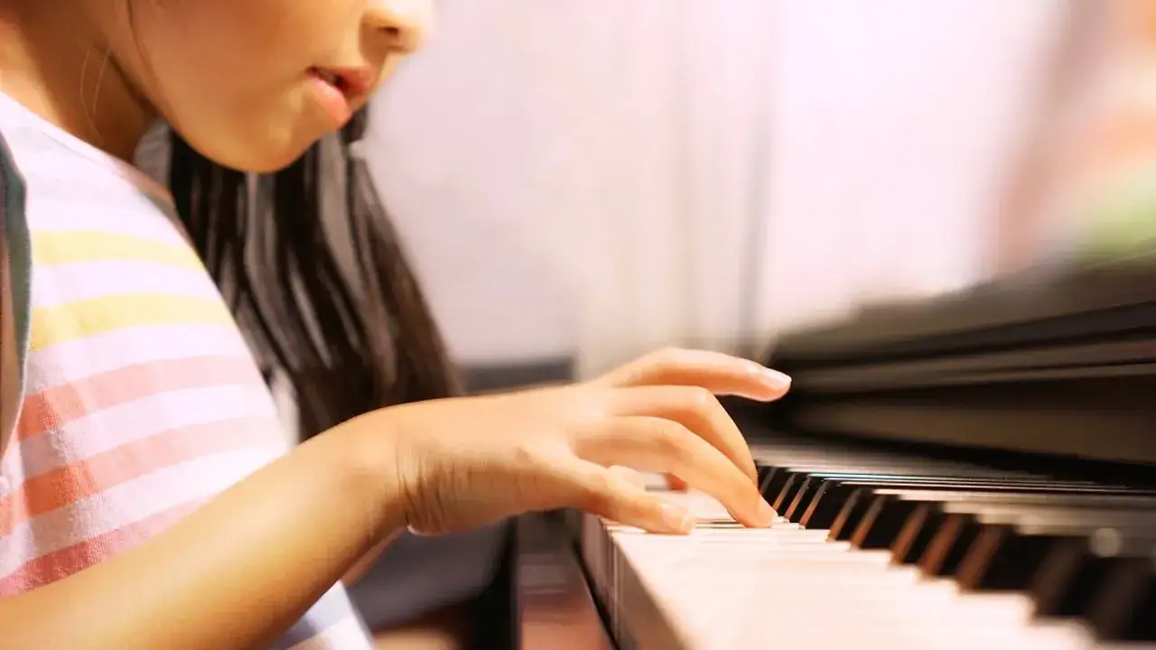 Bambina con orecchio assoluto e relativo suona il pianoforte, le dita danzano sui tasti.