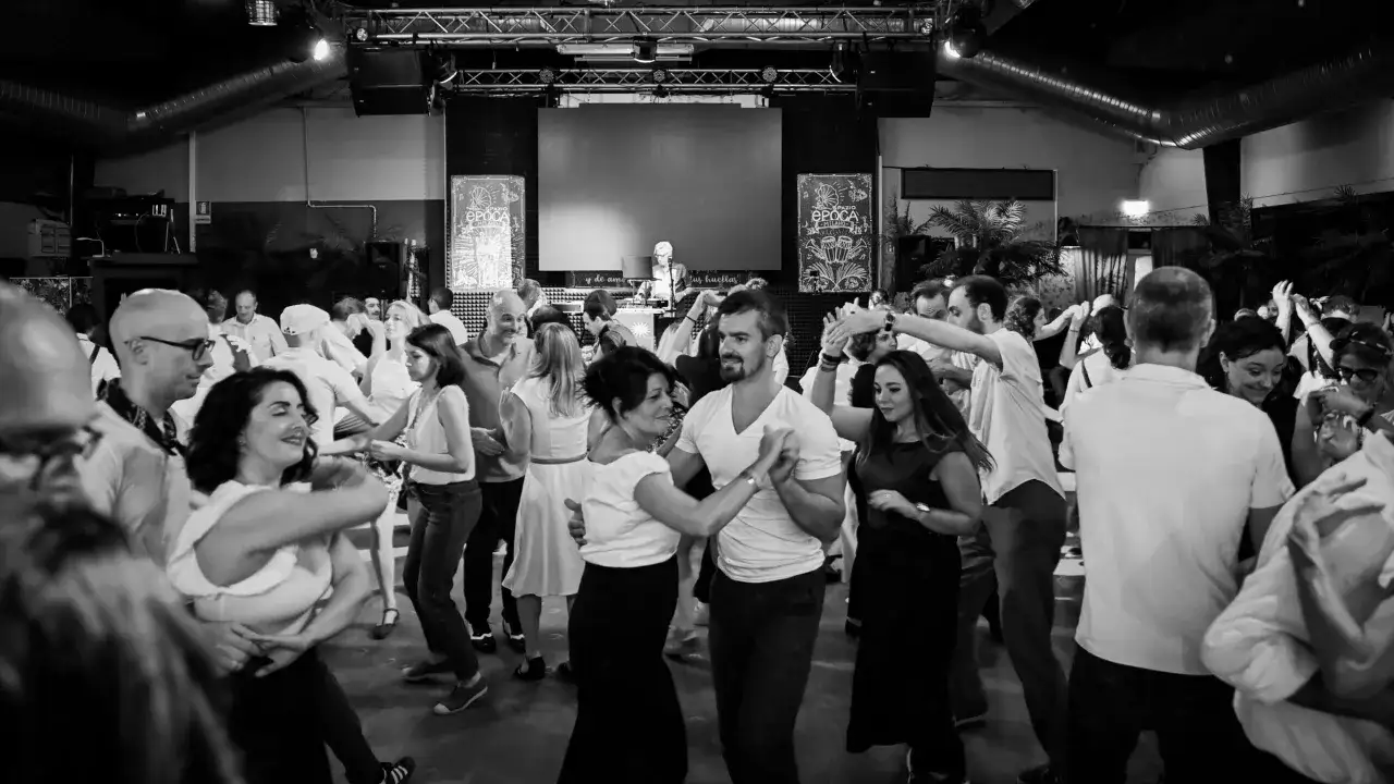 Coppie danzano con gioia al ritmo del lindy hop, un'esplosione di energia e sorrisi in pista.