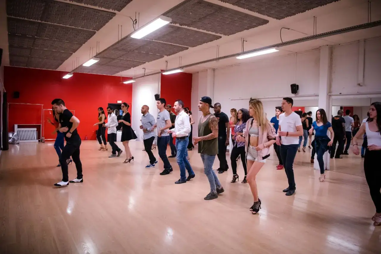 Persone che imparano a ballare alla scuola di salsa, con movimenti fluidi e sorrisi.