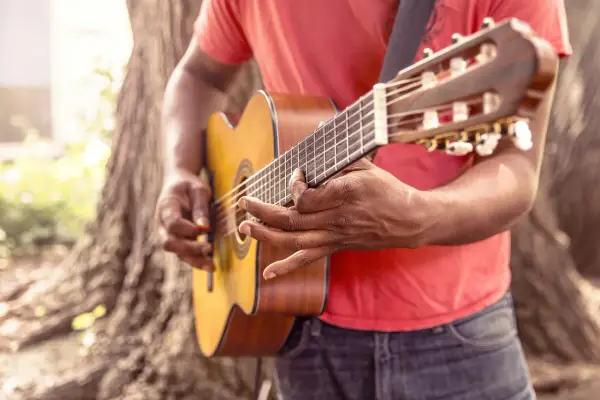 Uomo suona la chitarra acustica, ideale per imparare canzoni in inglese facili da cantare.