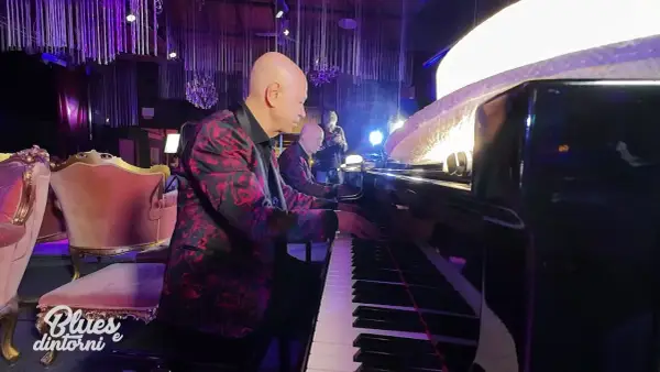 Pianista con giacca fiorata suona la canzone blues più famosa, accompagnato da un altro musicista.